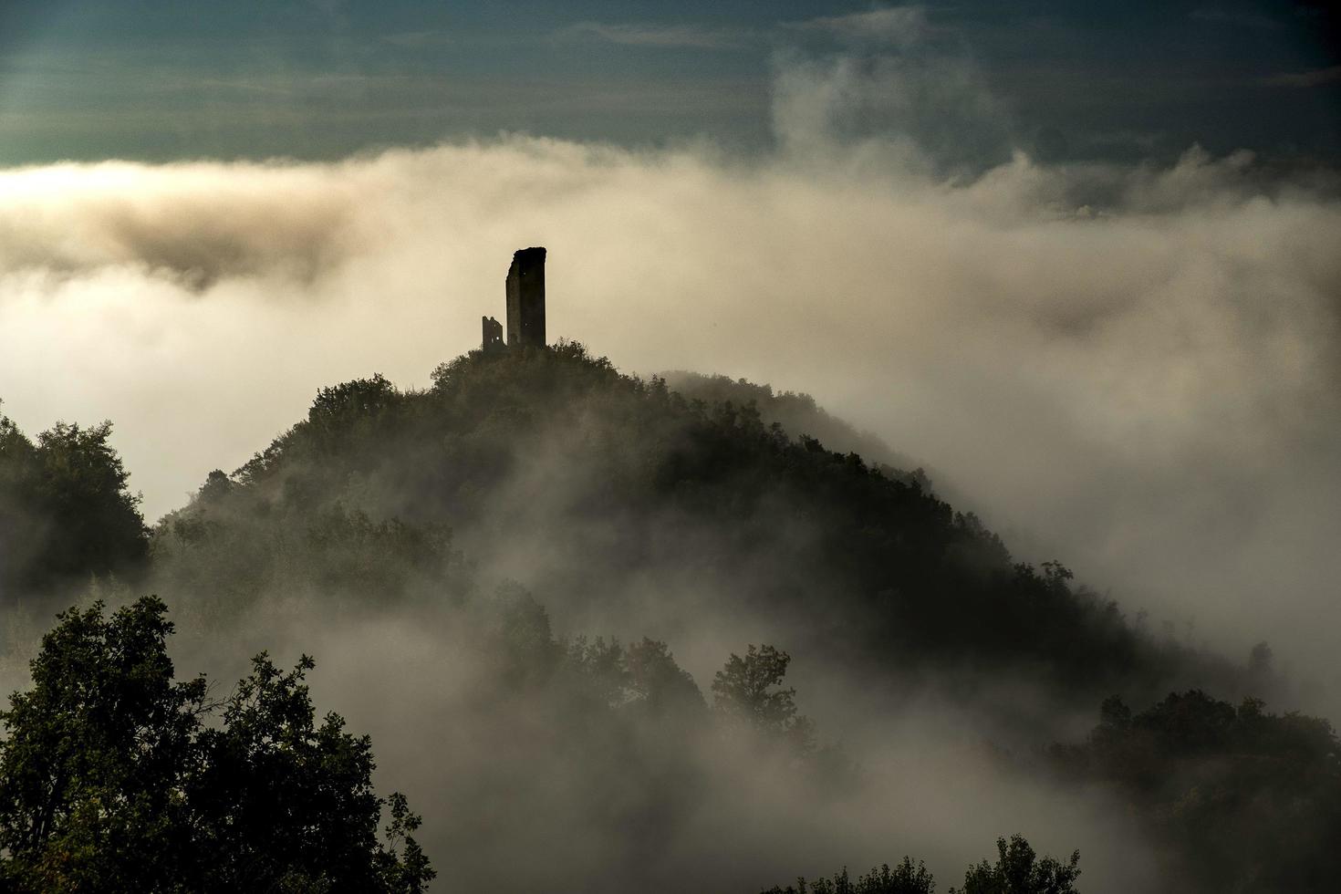 castle shrouded in morning fog on an autumn day in Italy photo