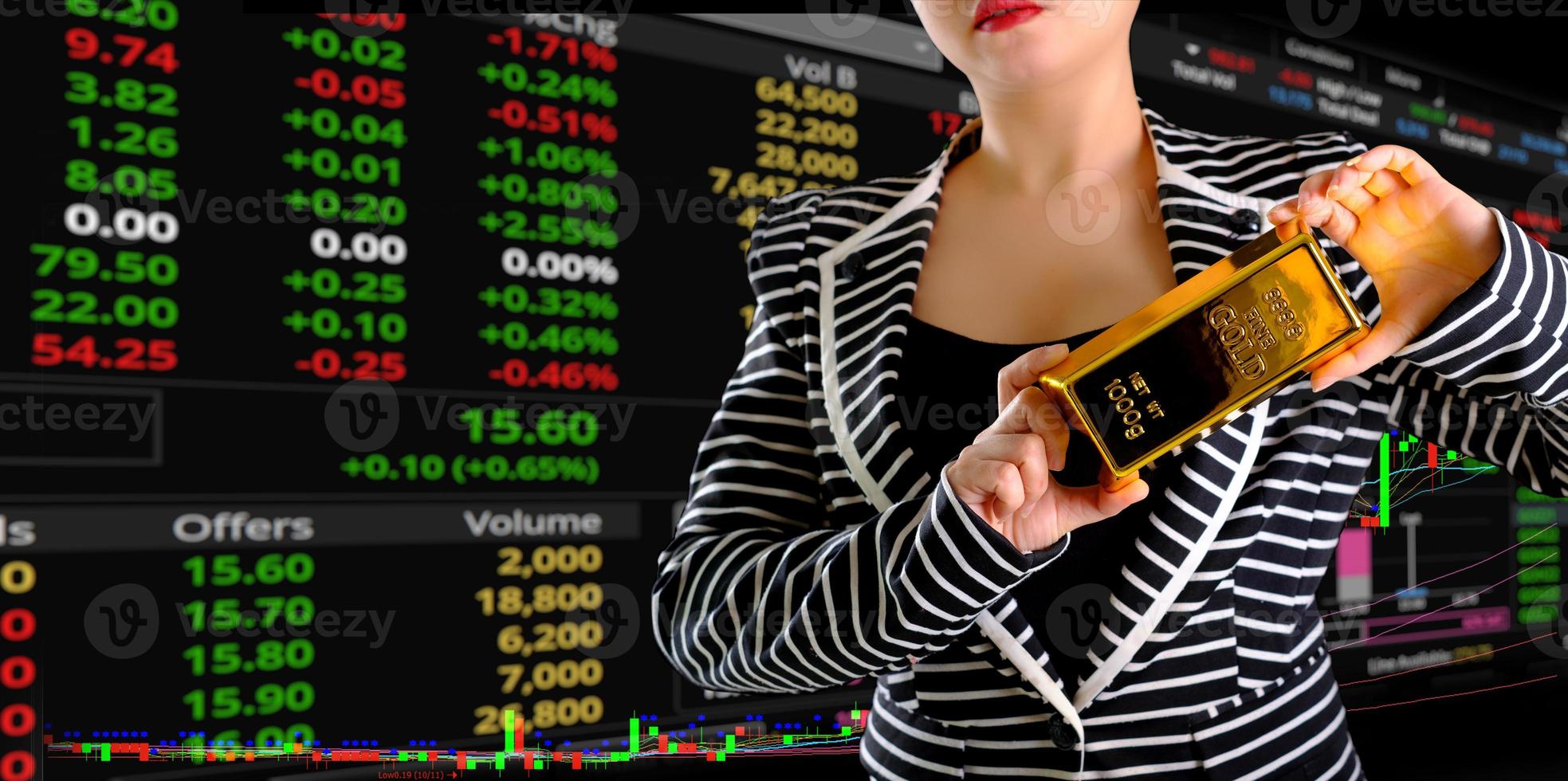 Business woman holding the gold bar at trading and chart background photo