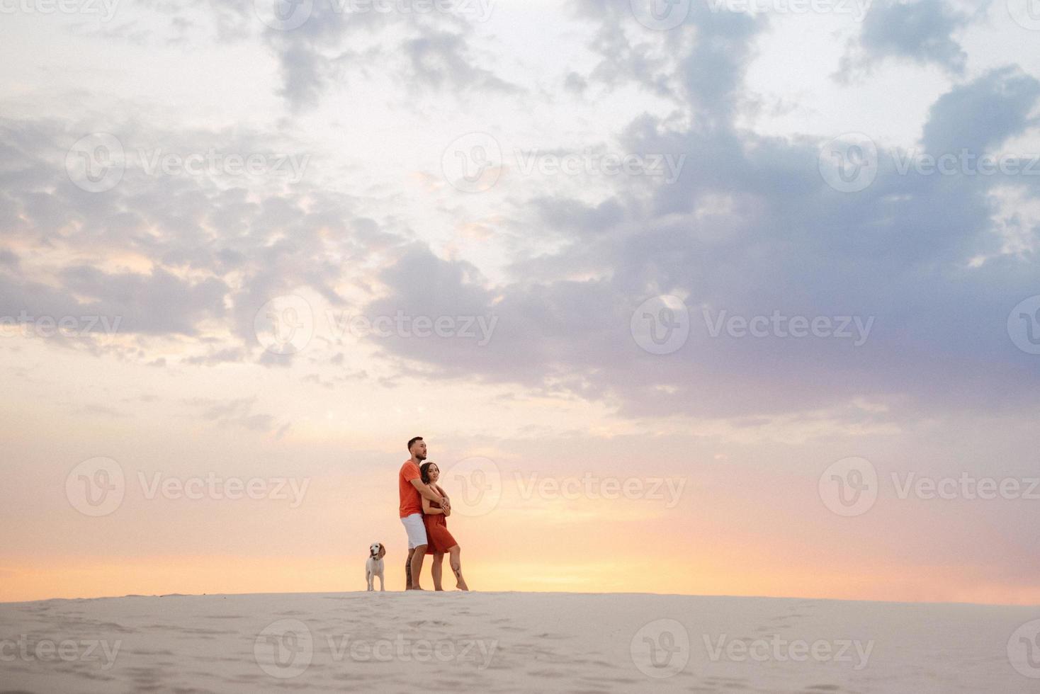 young couple in orange clothes with dog photo