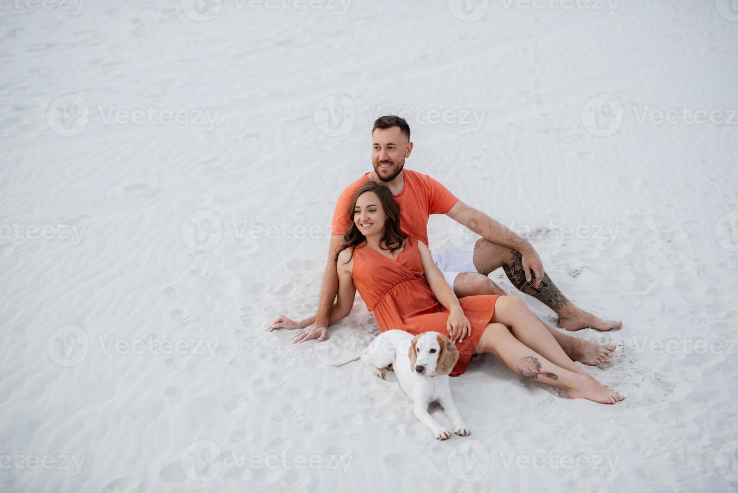 young couple in orange clothes with dog photo