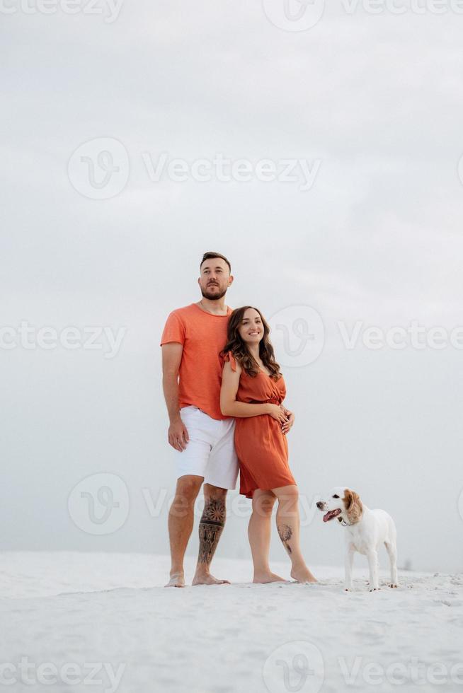 young couple in orange clothes with dog photo