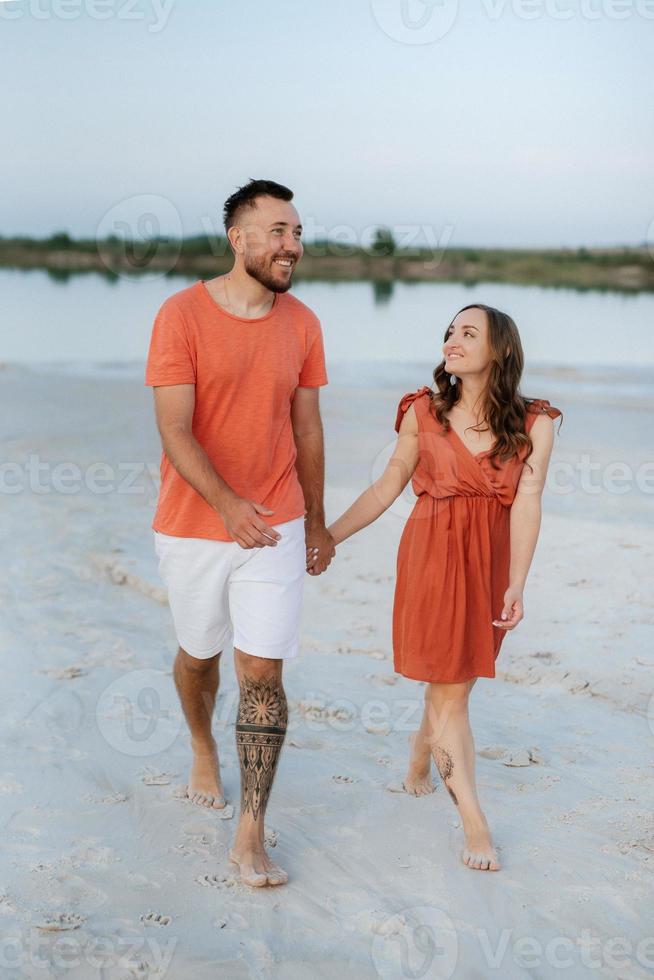 young couple in orange clothes with dog photo