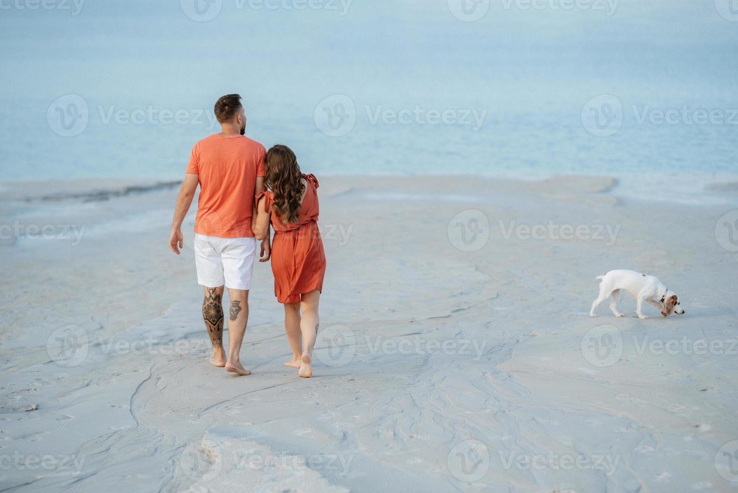 young couple in orange clothes with dog photo