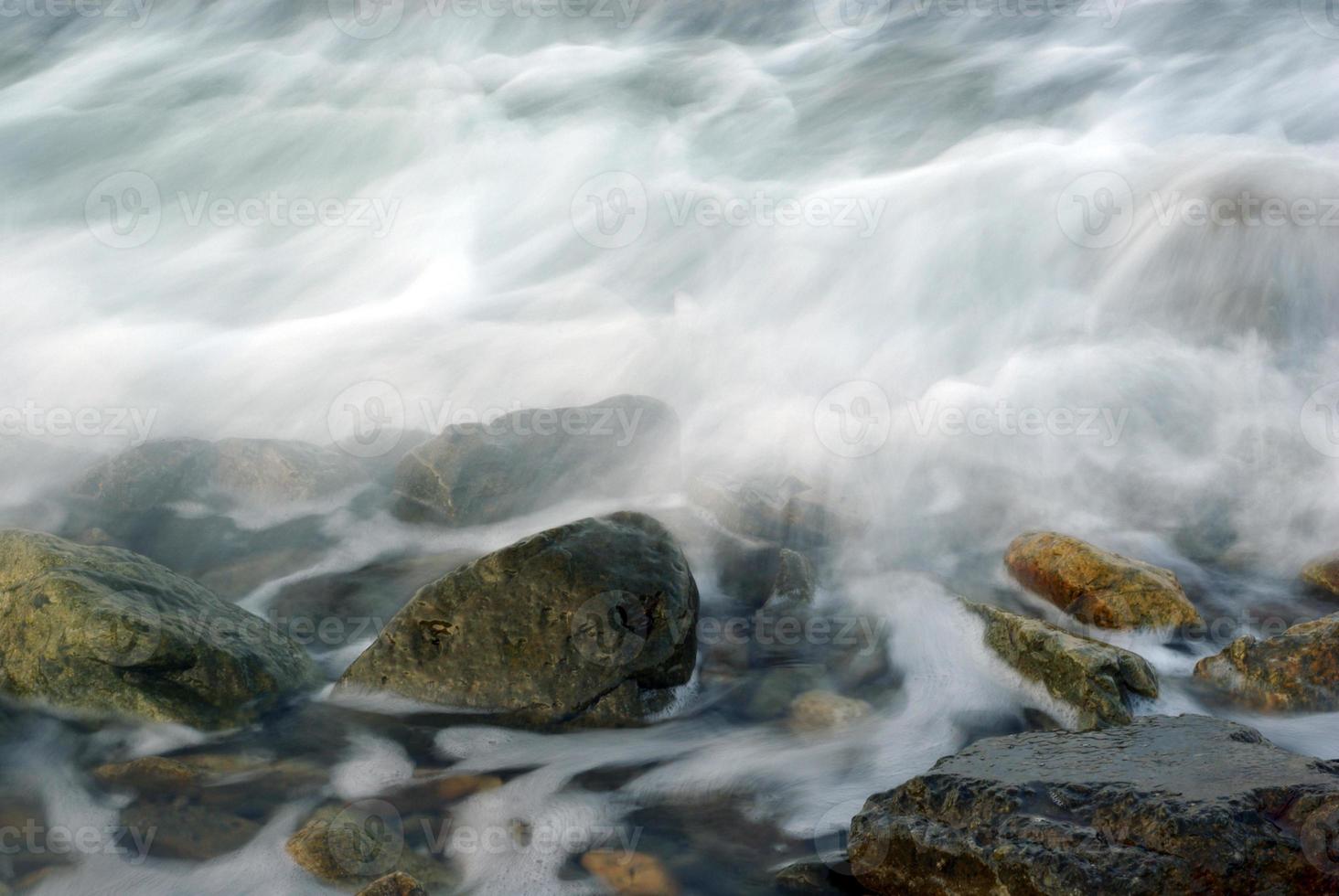 turbulencia de agua de mar y rocas en la costa foto