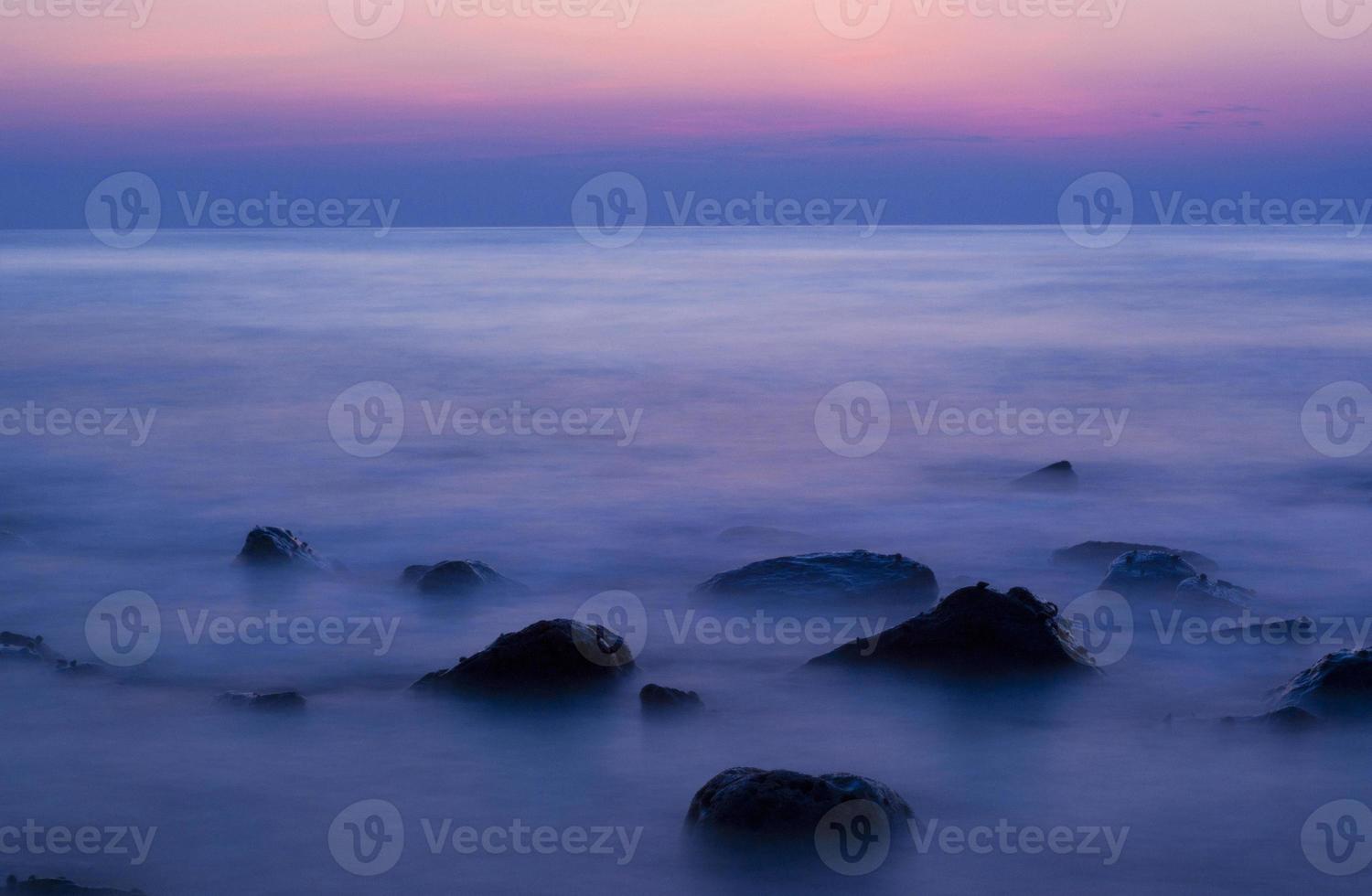 Soft waves on a rocky beach in the evening photo