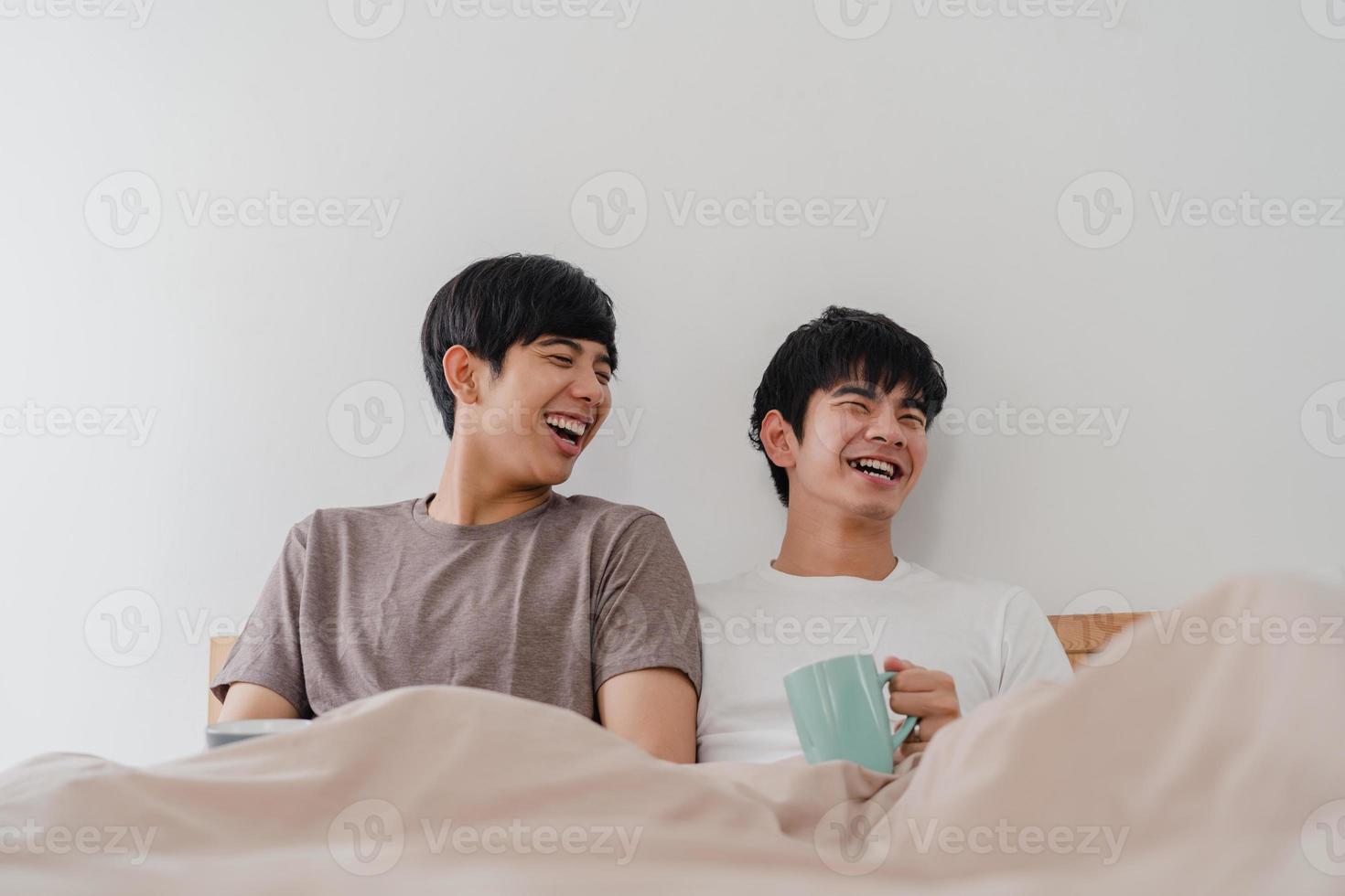 Asian Gay men couple talking having a great time at modern home. Young Asia lover male happy relax rest drink coffee after wake up while lying on bed in bedroom at house in the morning concept. photo