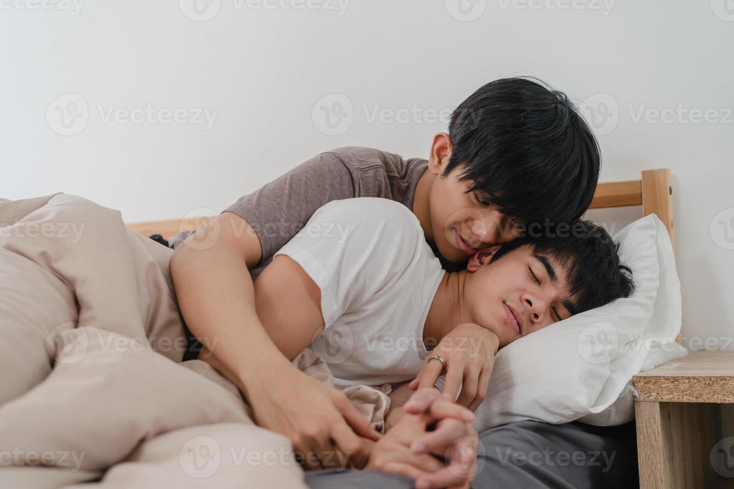 Asian Gay couple kiss and hug on bed at home. Young Asian LGBTQ men happy relax rest together spend romantic time after wake up in bedroom at home in the morning concept. photo