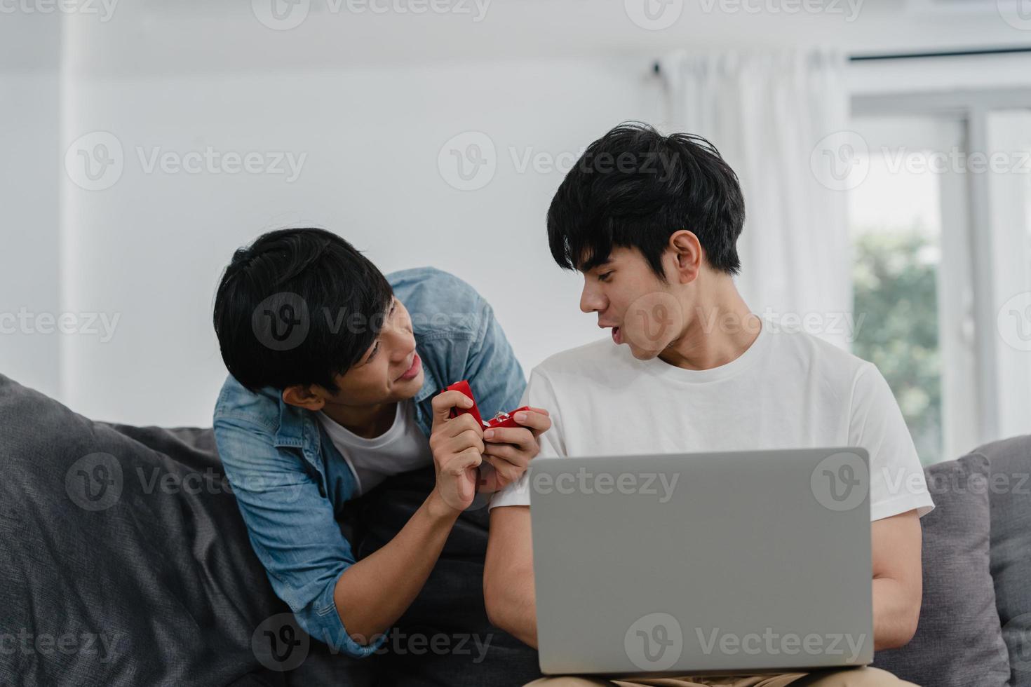 joven pareja gay asiática proponer en casa moderna, hombres lgbtq coreanos adolescentes felices sonriendo tienen tiempo romántico mientras proponen y matrimonio sorpresa usan anillo de bodas en la sala de estar en el concepto de casa. foto