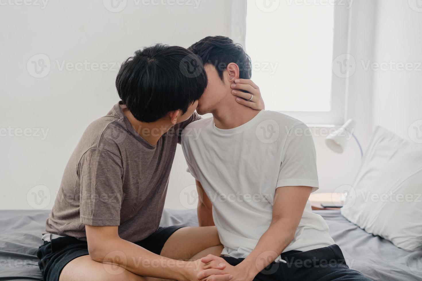 pareja gay asiática besándose en la cama en casa. jóvenes asiáticos lgbtq hombres felices relajarse descansar juntos pasar un momento romántico después de despertarse en el dormitorio en casa en el concepto de la mañana. foto