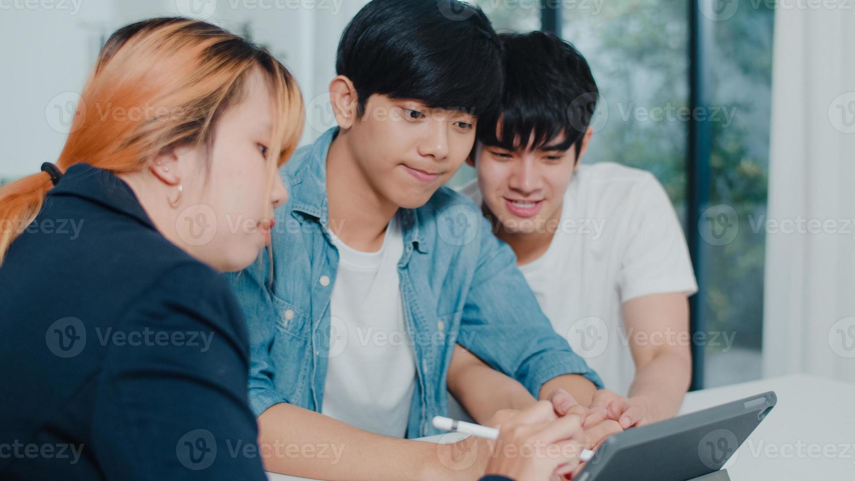 Asian Gay lgbtq men couple sign contract on tablet at home, Young couple consulting with real estate financial advisor, Buying new house and handshaking with broker in living room at house concept. photo