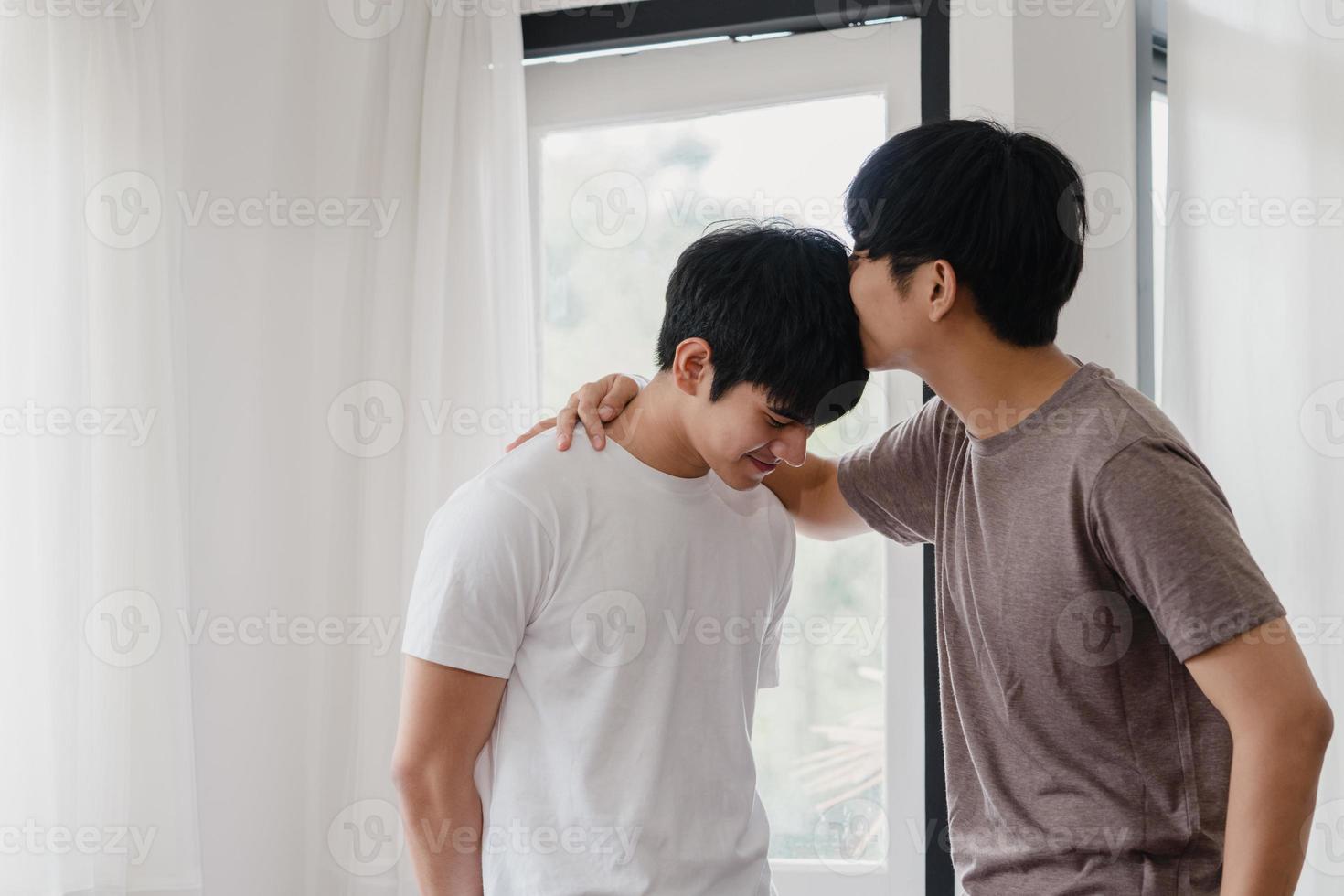 Pareja gay asiática de pie y abrazándose cerca de la ventana en casa. Hombres jóvenes asiáticos lgbtq besándose felices relajarse descansar juntos pasar tiempo romántico en la sala de estar de la casa moderna en el concepto de la mañana. foto