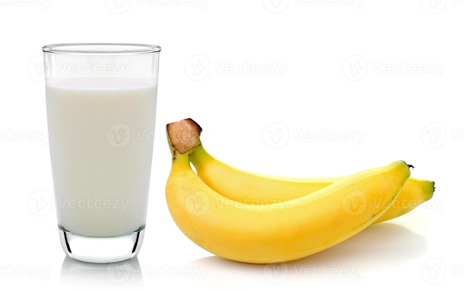 Vaso de leche con plátano sobre fondo blanco. foto