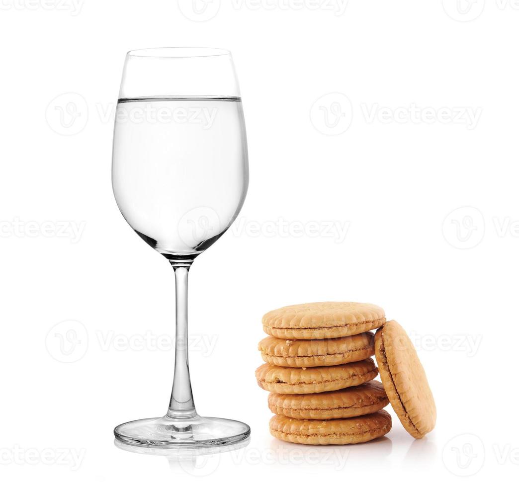 Vaso de agua y galletas sobre fondo blanco. foto