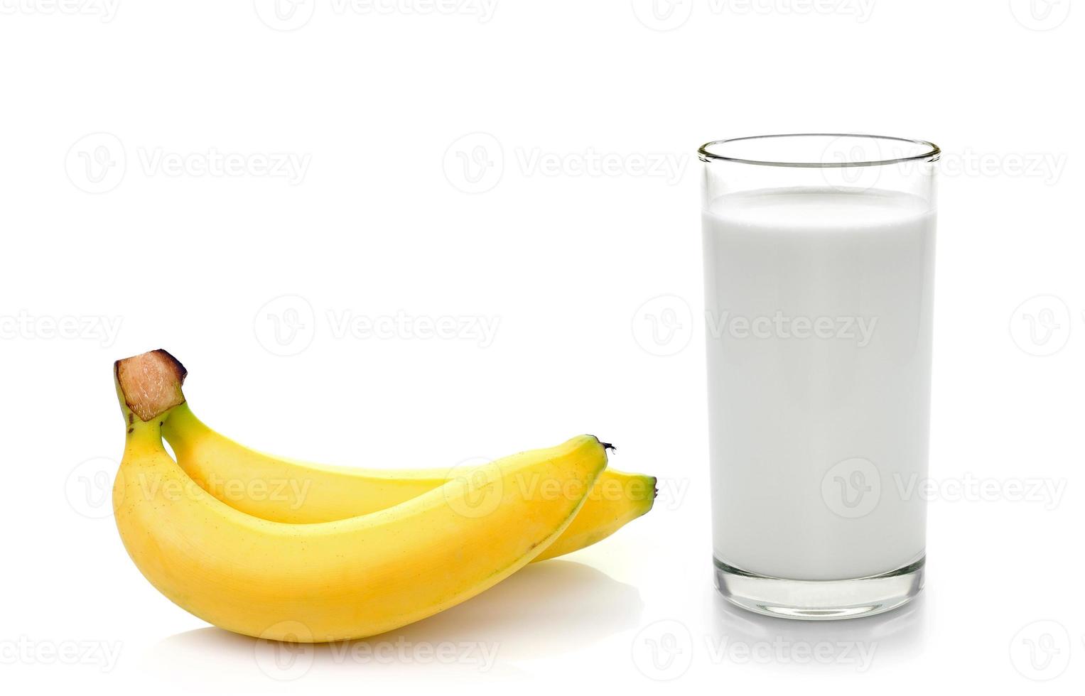 Vaso de leche con plátano sobre fondo blanco. foto