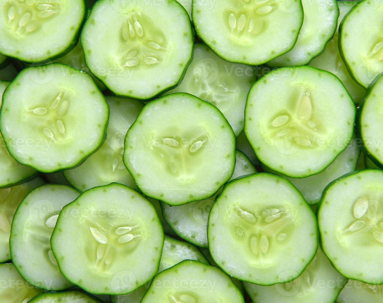 Pepino fresco y rodajas de fondo blanco. foto