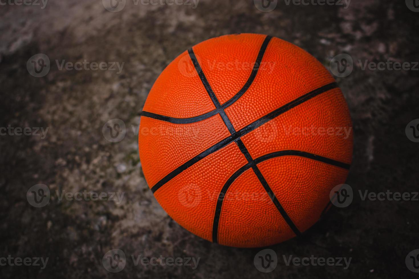 A dirty basketball on a concrete court after a street game. Dark background. photo