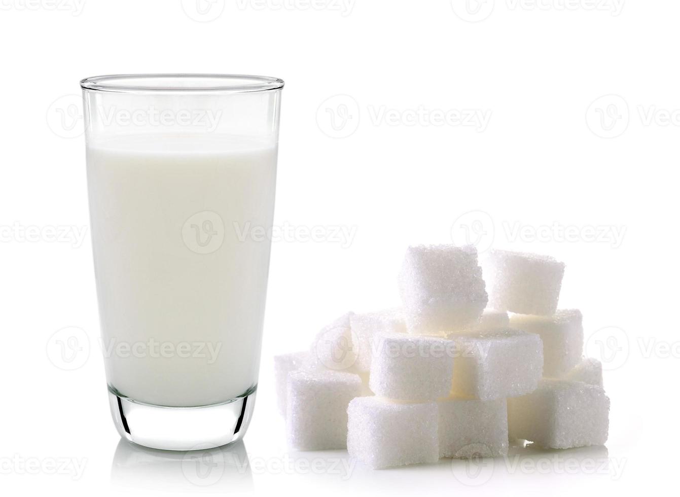 Vaso de leche y cubos de azúcar de caña aislado sobre fondo blanco. foto