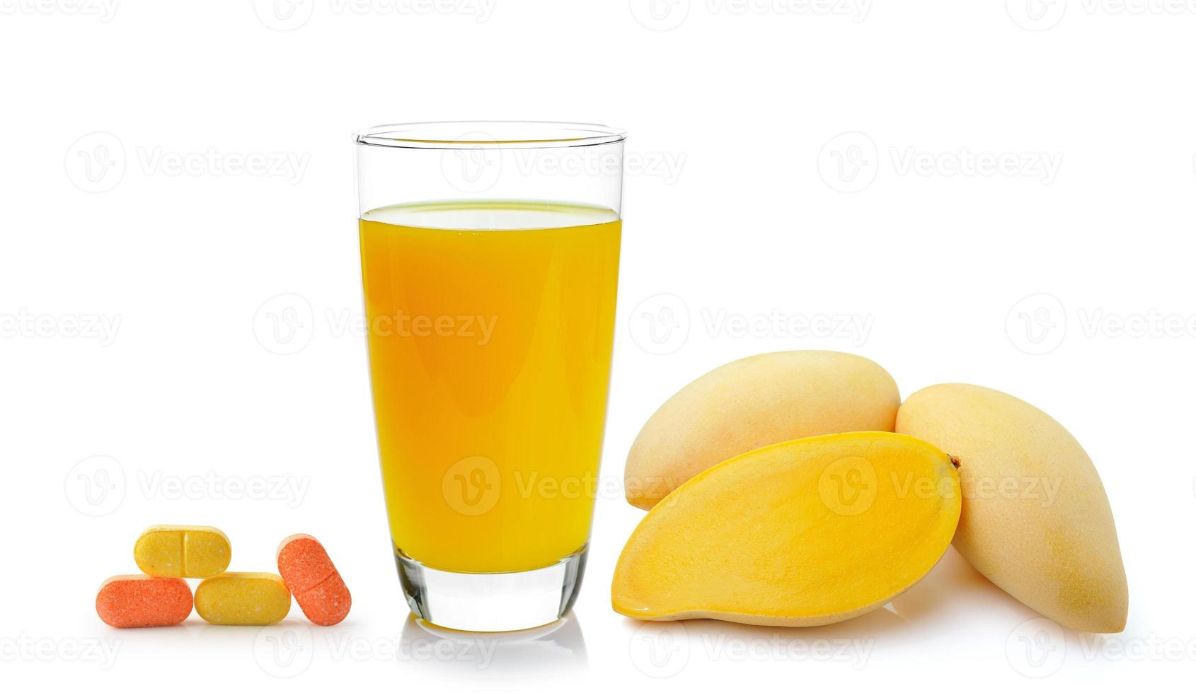 Jugo de mango en un vaso y vitamina C sobre fondo blanco. foto