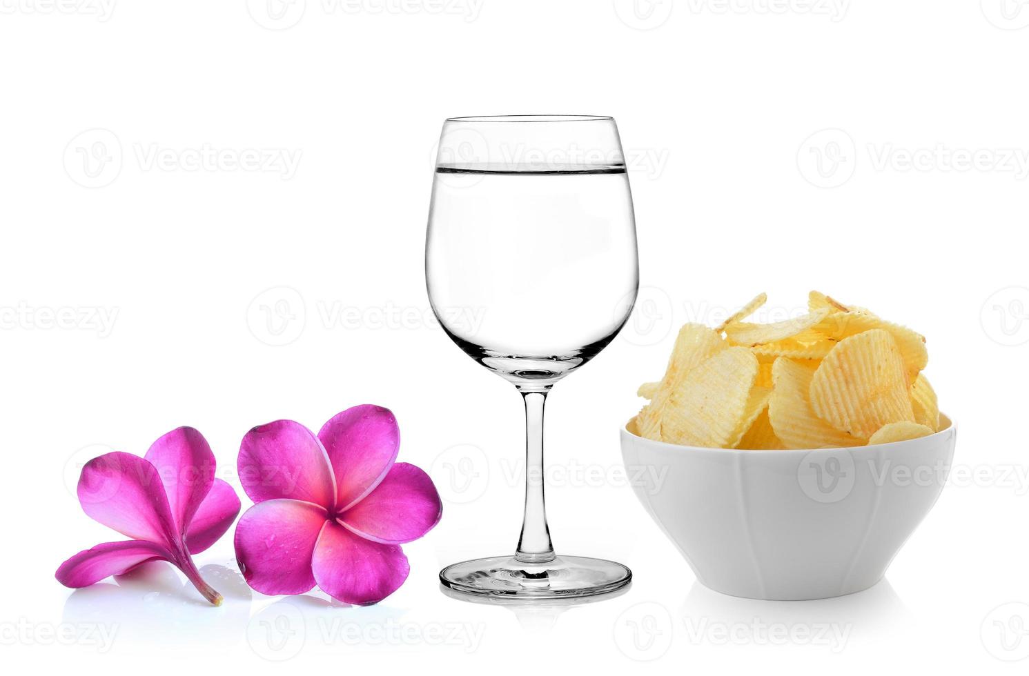 Vaso de agua flor de frangipani, tazón de papas fritas sobre fondo blanco. foto