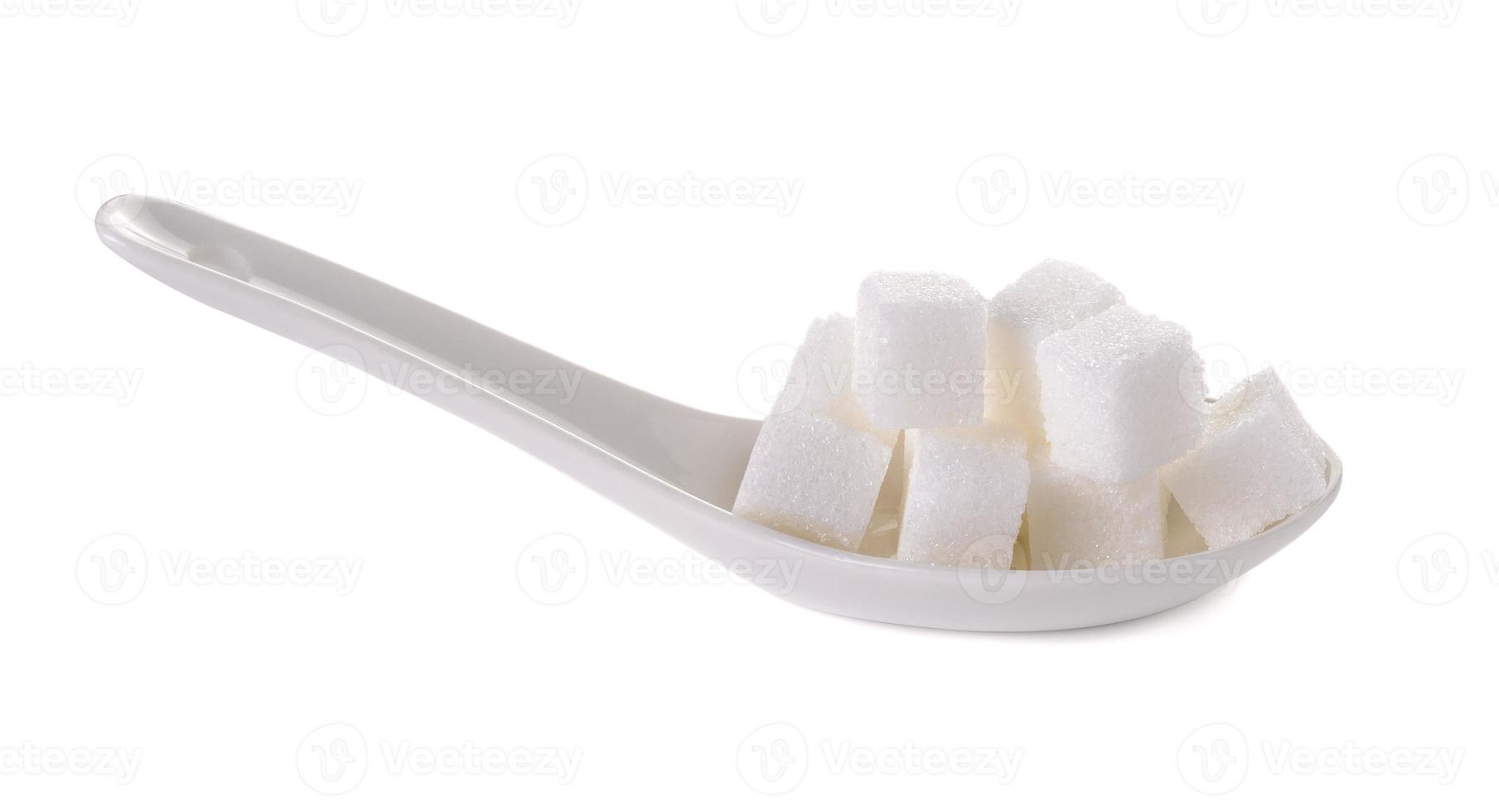Cubo de azúcares en cuchara blanca aislado sobre fondo blanco. foto