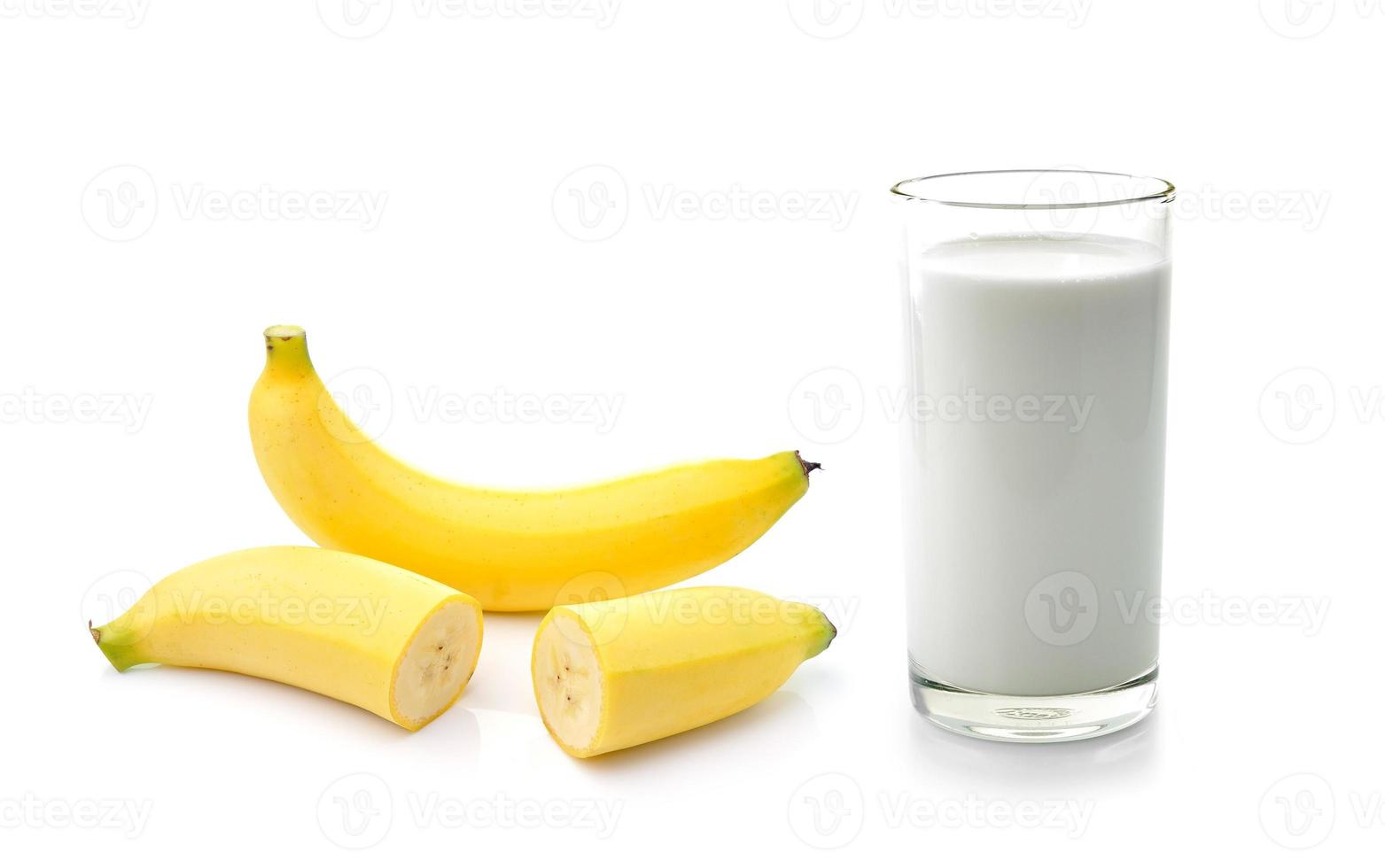 Vaso de leche con plátano sobre fondo blanco. foto