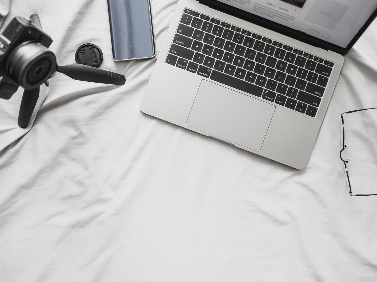 Above view of laptop computer camera and smartphone on bed. Concept of blogger and working at home digital lifestyle photo