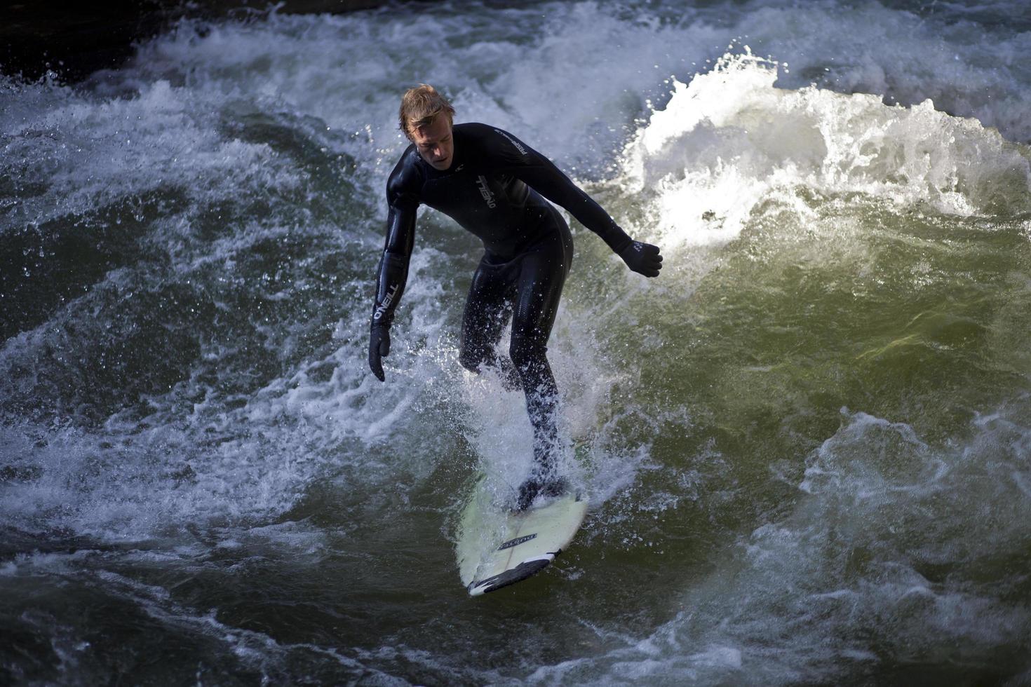 MUNICH, GERMANY, OCTOBER 23 - Unidentified surfer in the Eisbach river in English Garden in Munich, Germany at October 23, 2011. The first surfers discovered the Eisbach in the 1970's. photo