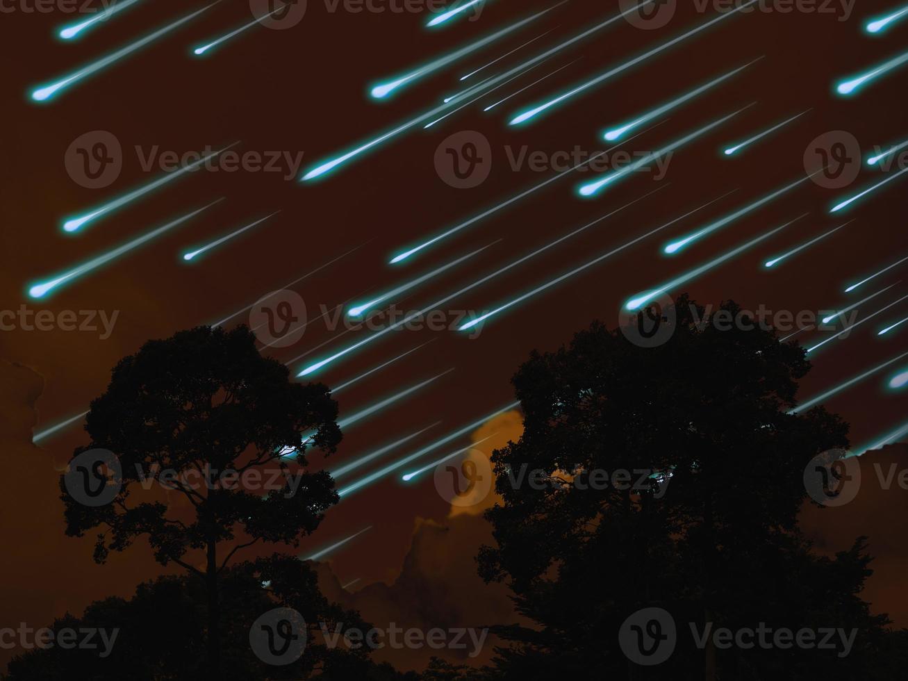 Meteorito en el cielo nocturno, nube de color naranja oscuro y árbol en el bosque tropical. foto