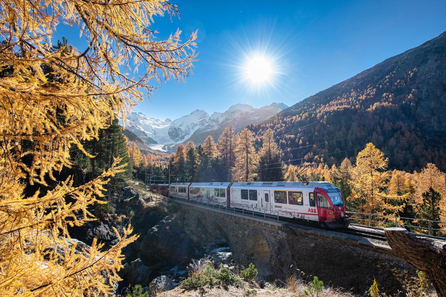 Tourist train on the swiss alps passes through mountains photo