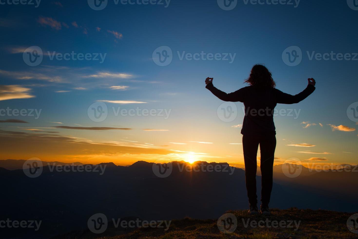 Chica en meditación de yoga en la cima de una montaña al atardecer foto