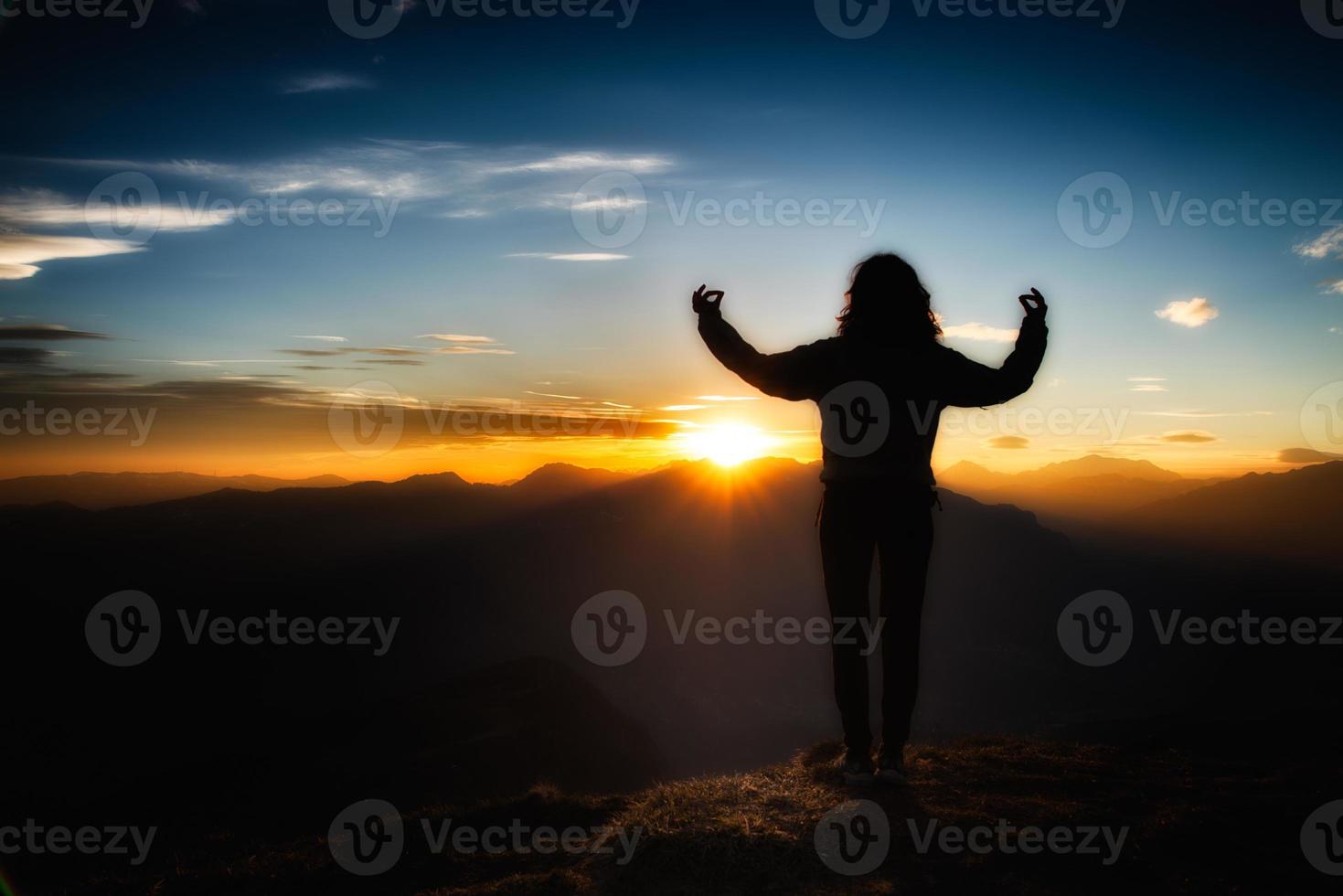 Chica en meditación de yoga en la cima de una montaña al atardecer foto