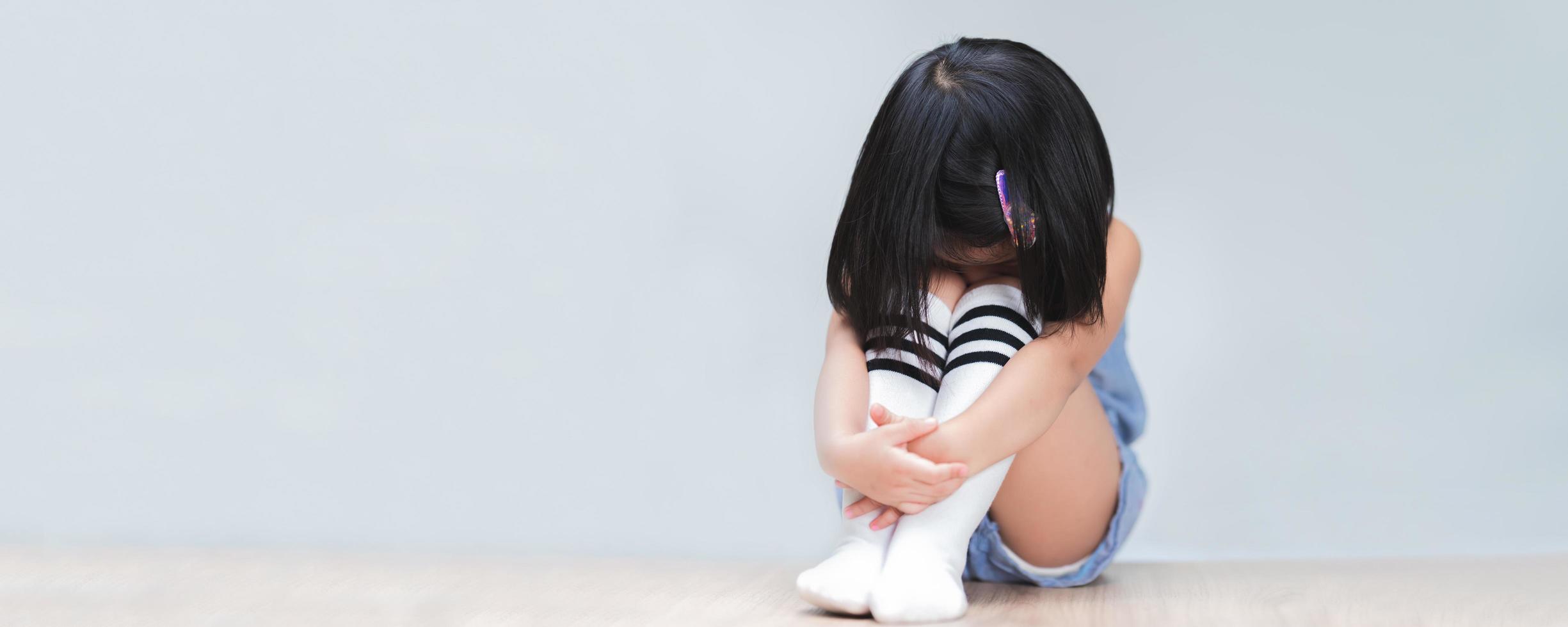 La niña se sintió afligida, sentada y abrazándose de rodillas e inclinando su cabeza con dolor. concepto de salud mental de niños y adolescentes. foto