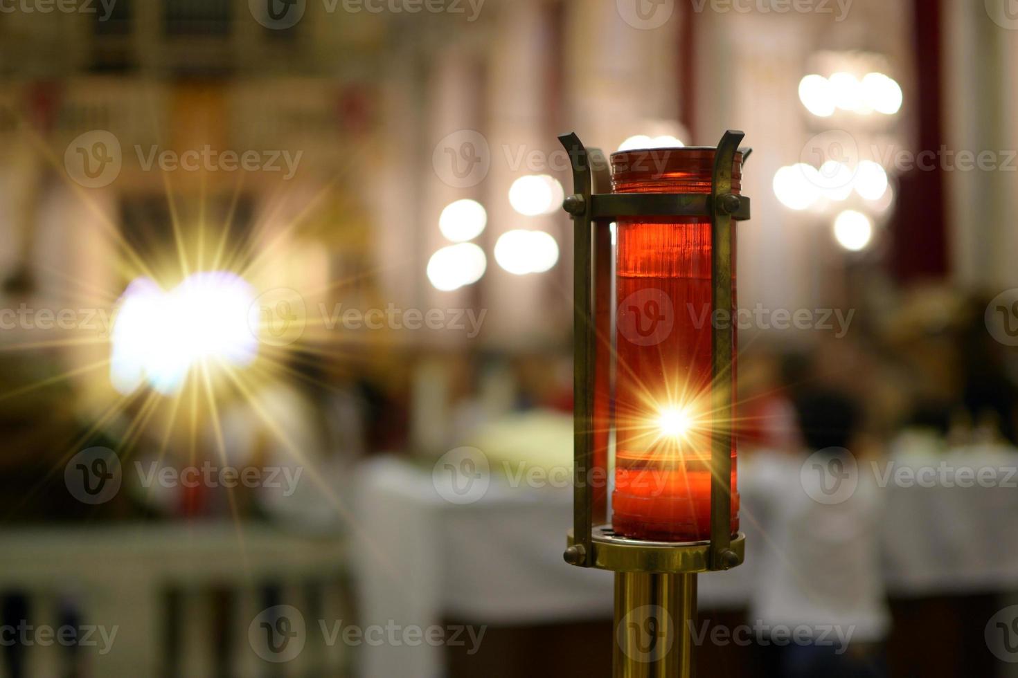 Vela votiva encendida dentro de una iglesia que representa la luz divina. Luz divina. foto