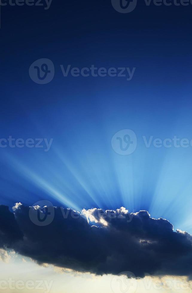 rayos de sol que se elevan desde detrás de una nube foto