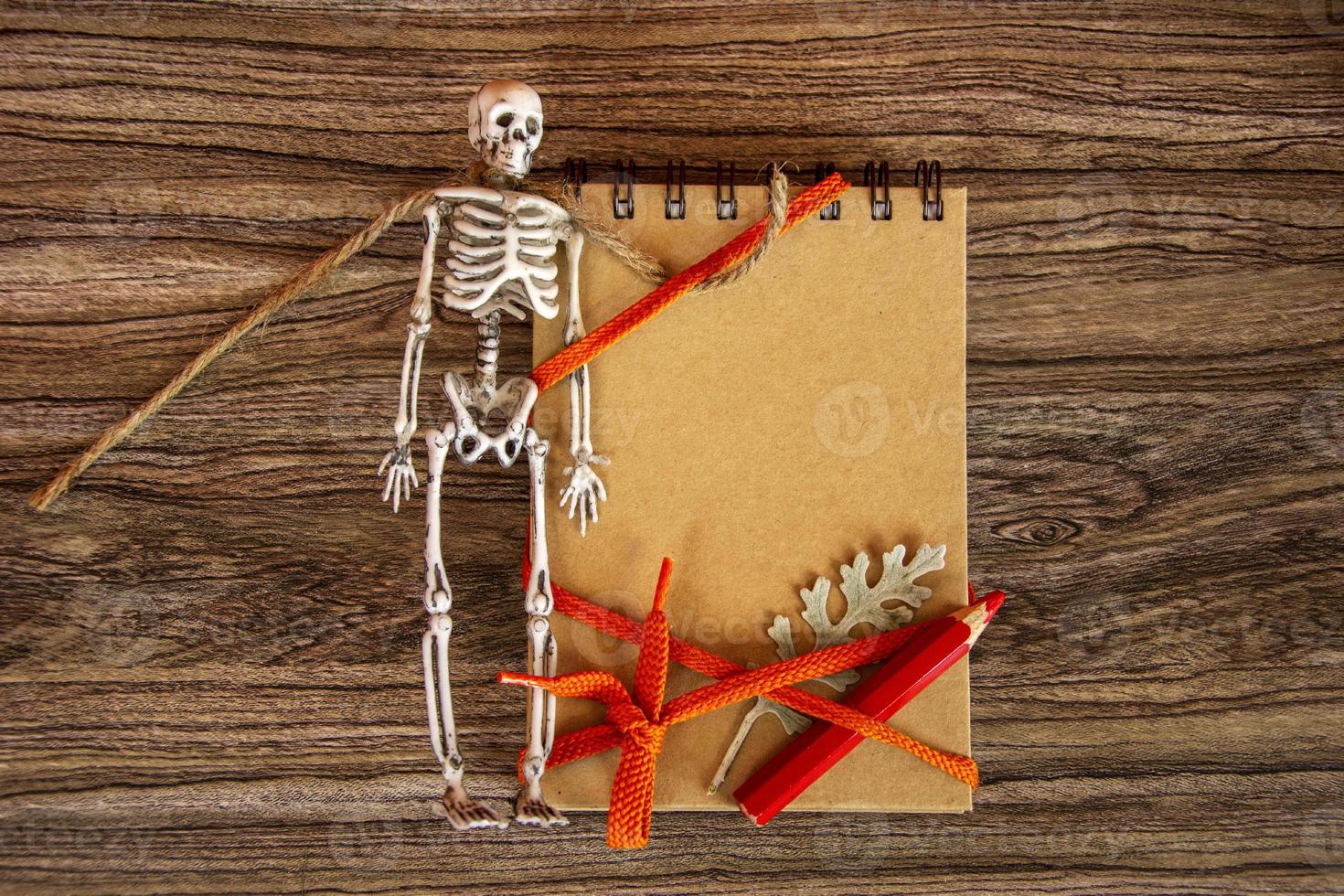 Autumn background with notepad, skeleton and dry leaves. Halloween card. photo