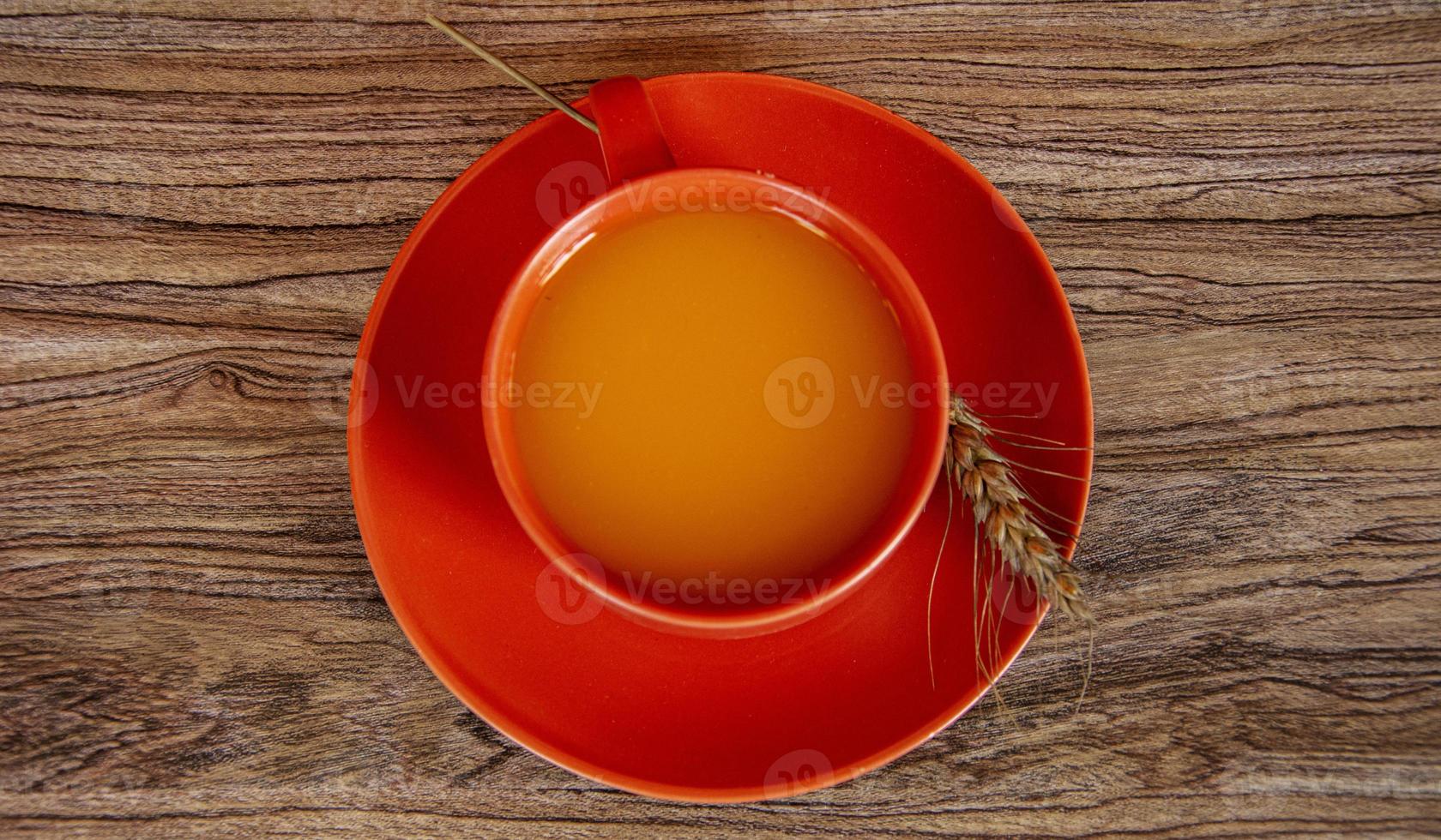 Cup with pumpkin juice and cereal on a wooden background. Halloween still life. photo