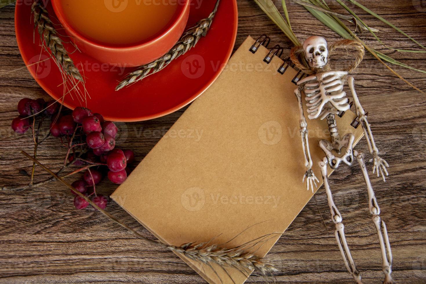 Halloween card with skeleton and notepad. Autumn background with rowan and a cup of pumpkin juice. photo