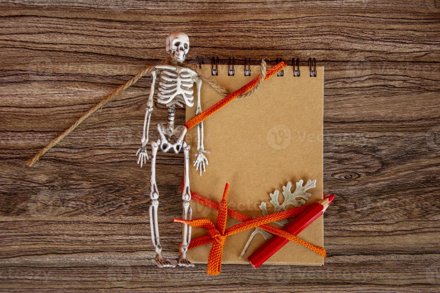 Halloween card. Autumn background with notepad, skeleton and dry leaves. photo