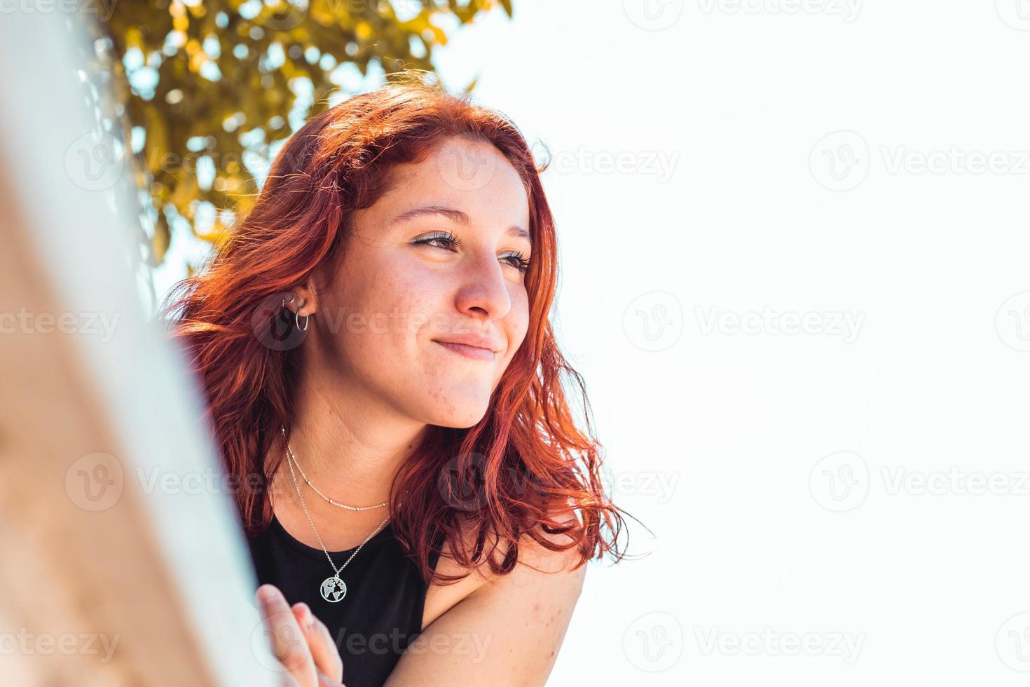 Feliz chica pelirroja en un parque, primer plano foto