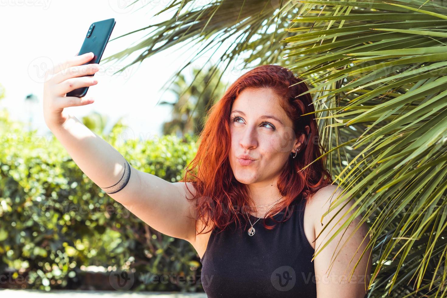 Mujer caucásica tomando un selfie con smartphone al aire libre en el parque foto