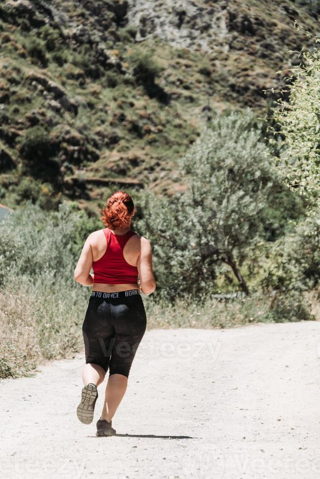 Active girl running at mountain, rural way photo