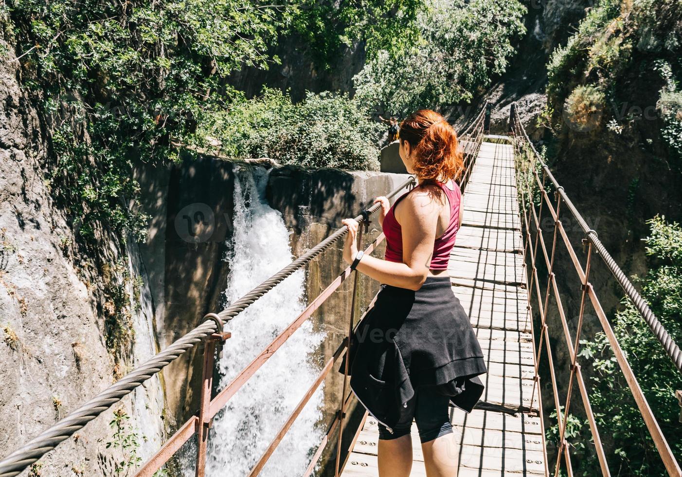 Mujer joven en un puente colgante caminando por la ruta de los cahorros, Granada, España foto