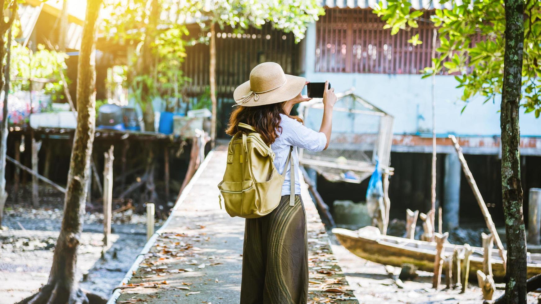 las niñas turistas caminando tomando fotografías el estilo de vida de los aldeanos en las aldeas rurales ban bang phat - phangnga. verano, lago, vacaciones, viajes a tailandia. mochila. teléfono móvil, fotografía. foto