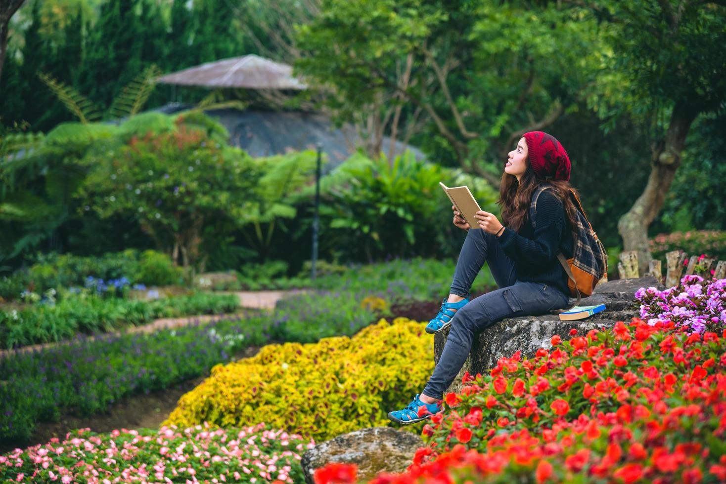 mujer viaje naturaleza en el jardín de flores. relájese sentado en las rocas y leyendo libros en medio de la naturaleza en el parque nacional doi inthanon. foto