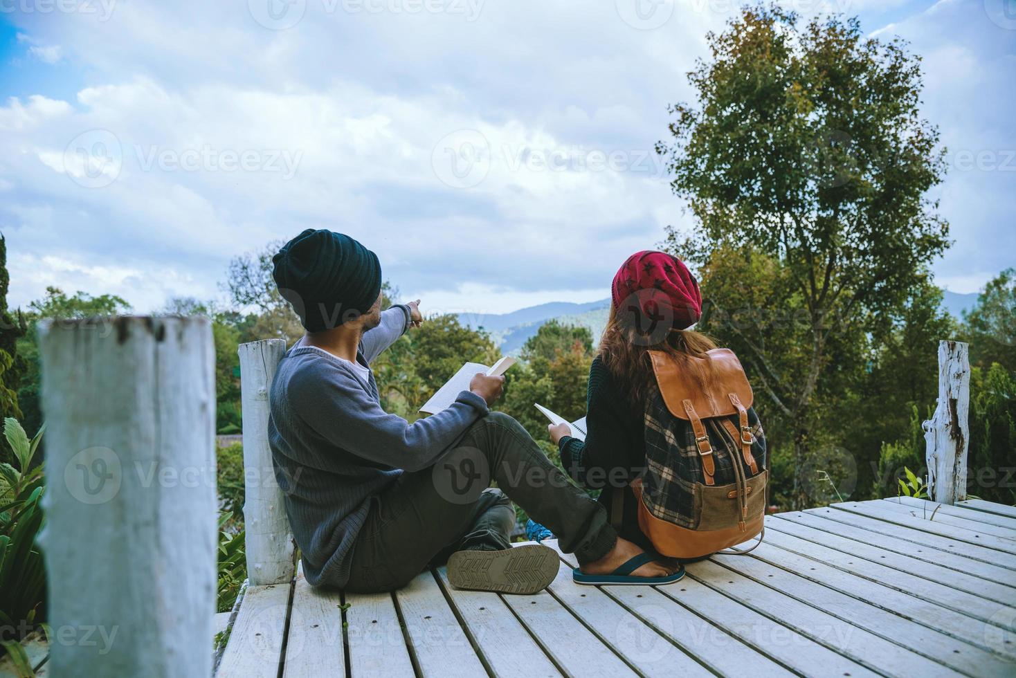 pareja amante viajes naturales en la montaña, sentarse relajarse leyendo libros en medio de la naturaleza en el puente de madera blanca. foto