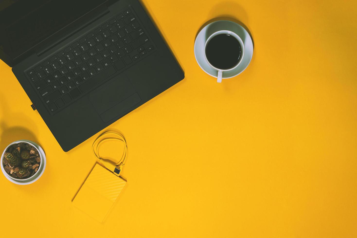 Conceptual workspace, Laptop computer and coffee cup, with Camera and Cactus tree. External hard disk with USB on pastel background yellow. Top view. Flat lay. summer photo