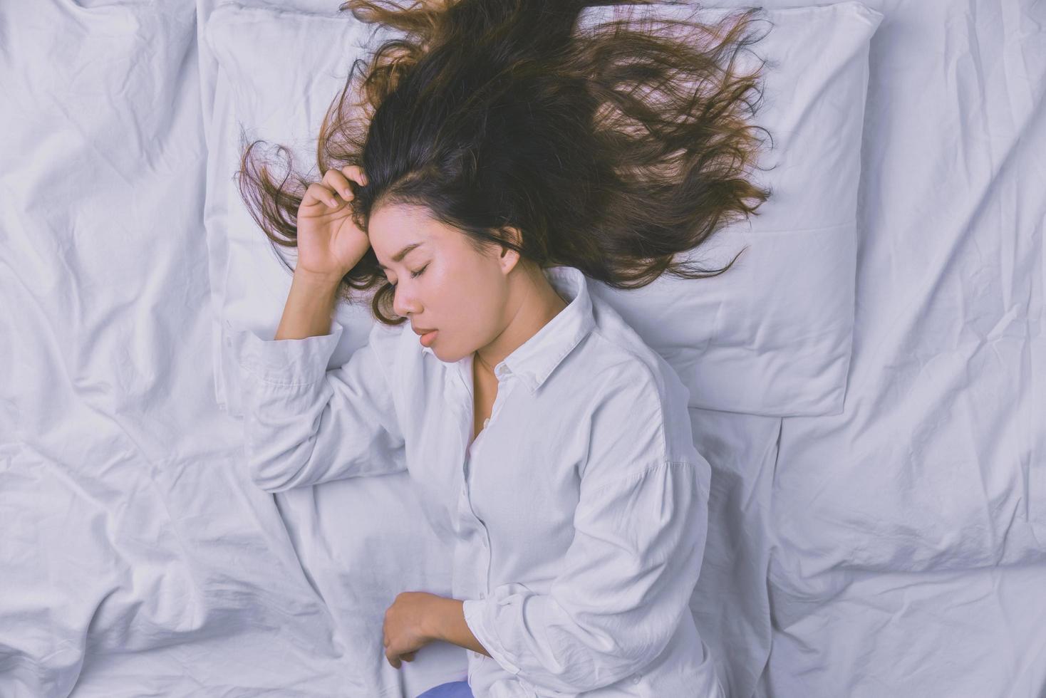 mujer joven durmiendo en la cama. Vista superior de la mujer joven acostada durmiendo bien en la cama. durmiendo relajarse, joven sonriente bonita dama yace en la cama. relajante, durmiendo. foto