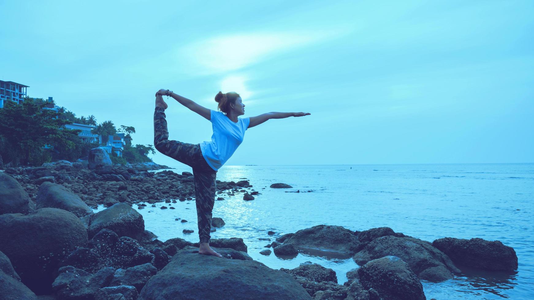 viaje de mujer asiática relajarse en las vacaciones. jugar si yoga. sobre las rocas junto al mar. foto