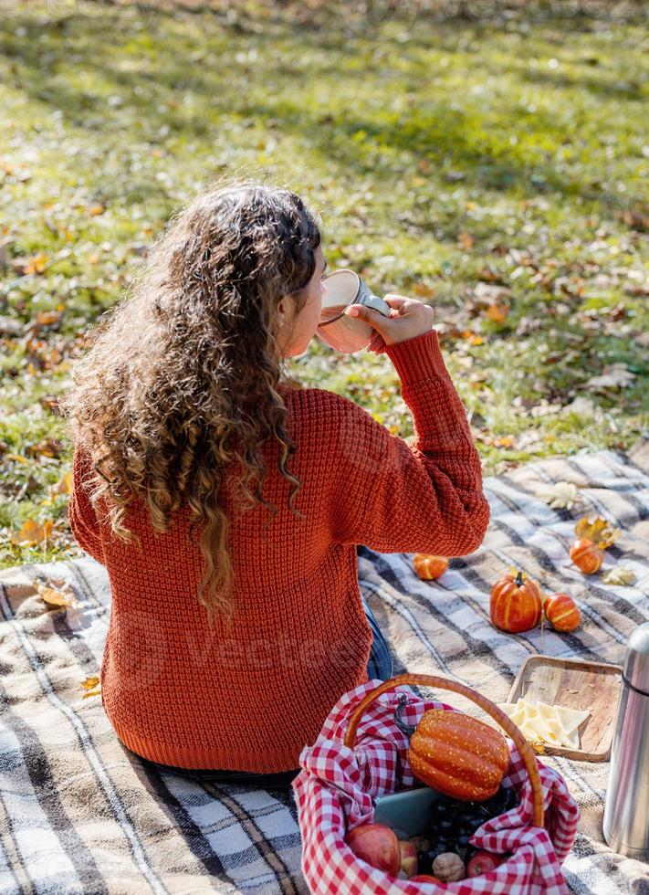 Bella mujer en suéter rojo en un picnic en un bosque de otoño foto