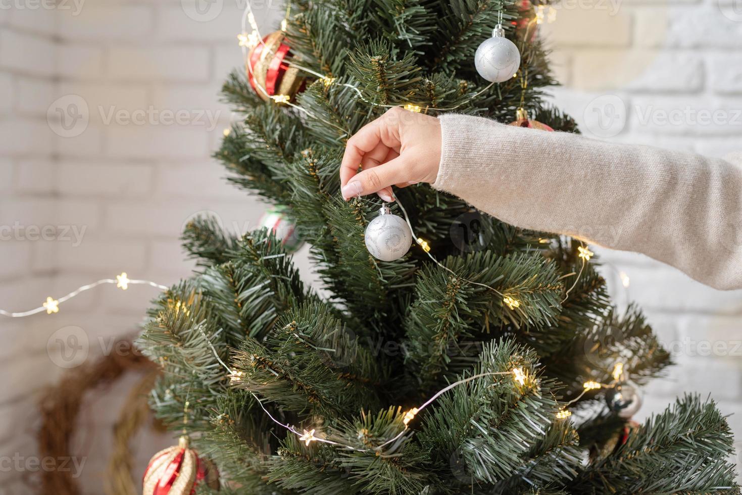 mano de mujer decorando el árbol de navidad con luces de colores foto